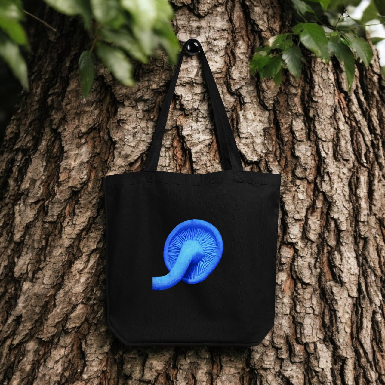 Blue Rhodocollybia black tote bag hanging from a tree