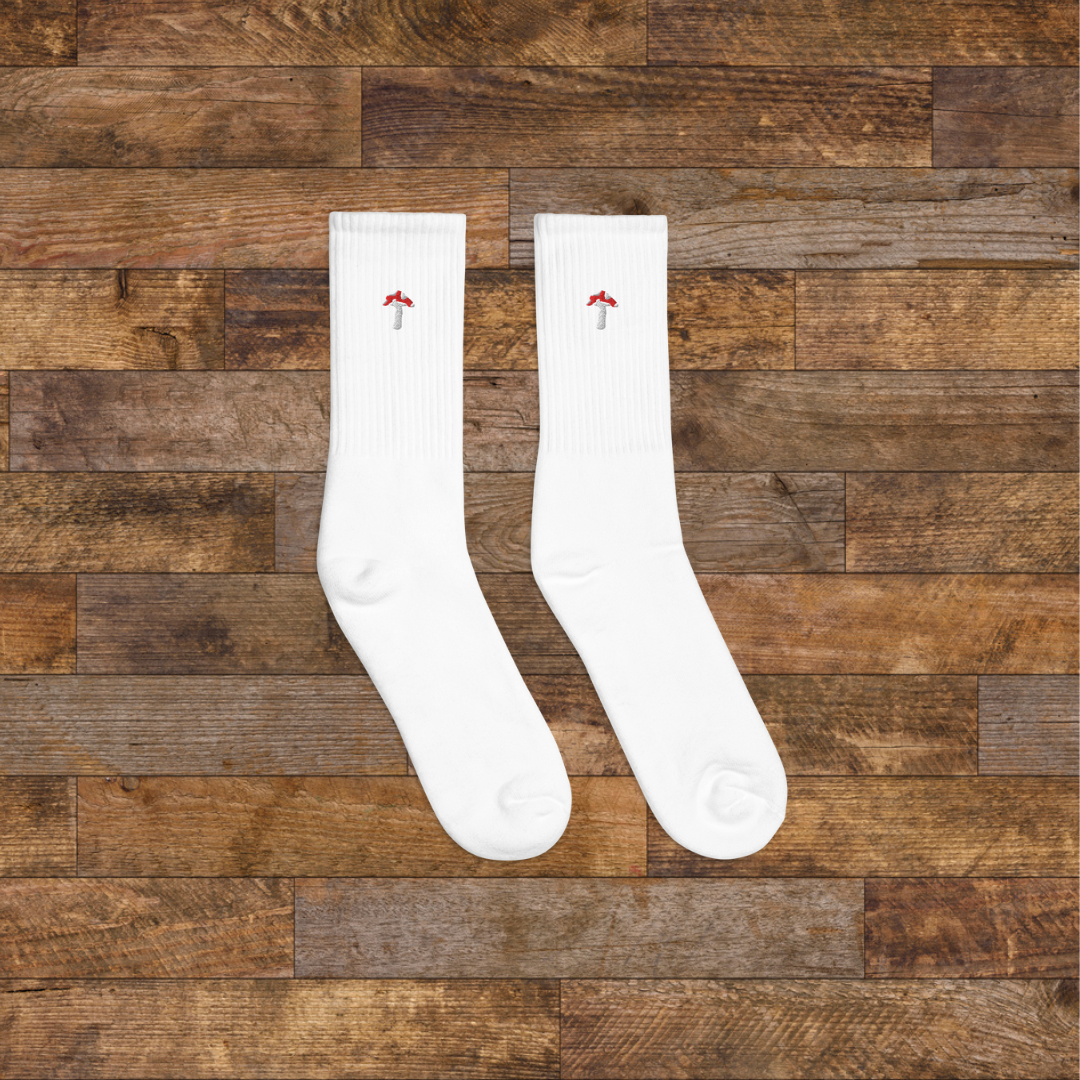 right white Embroidered Mushroom Crew Socks - ribbed knit with fly agaric red mushroom ankle design, wooden background.