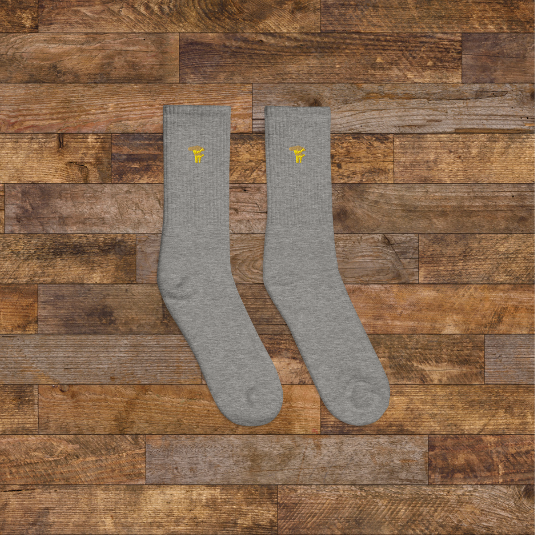 Right grey Embroidered Mushroom Crew Socks - ribbed knit with Chanterelle yellow mushroom ankle design, wooden background.