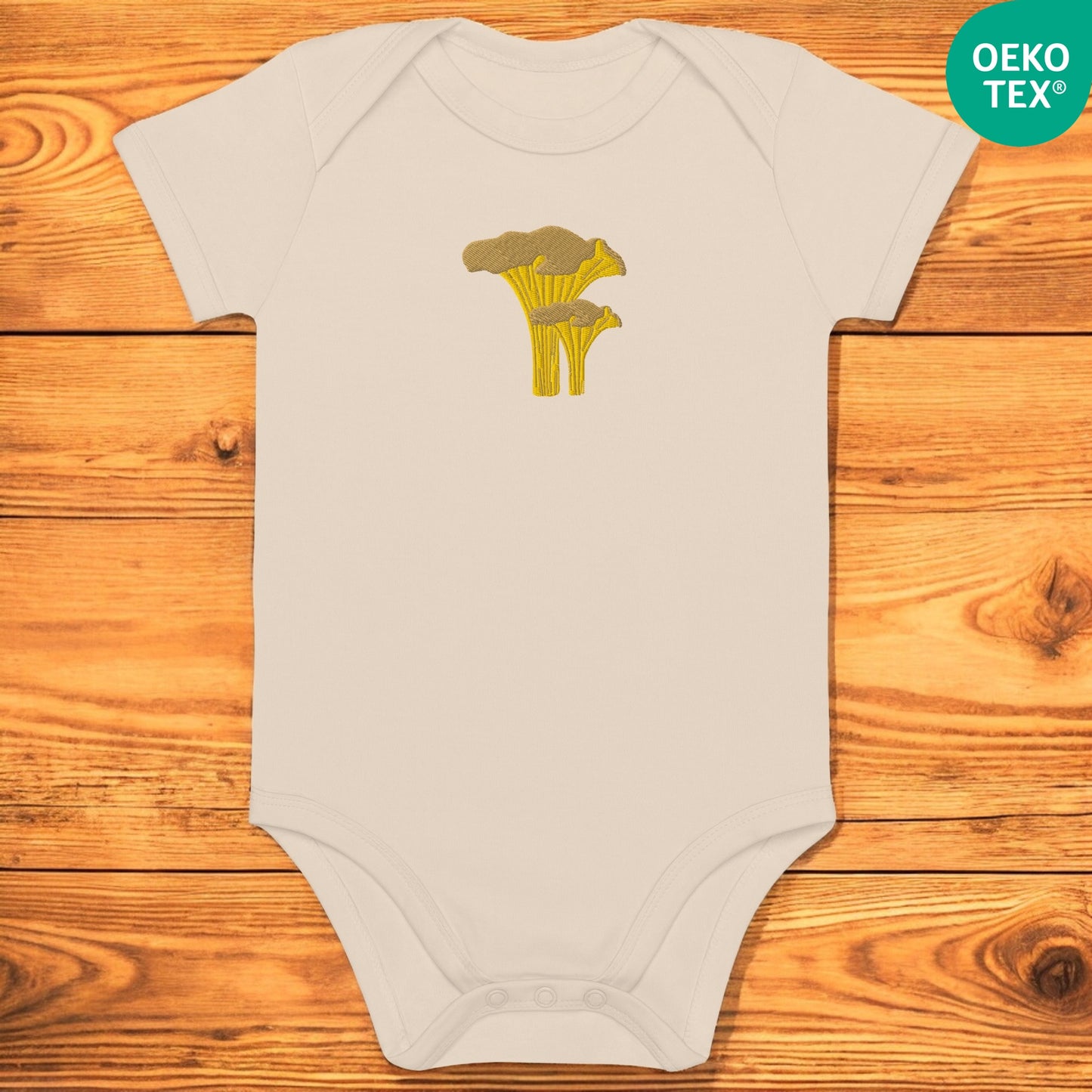 Beige baby body with chanterelle on a wooden floor