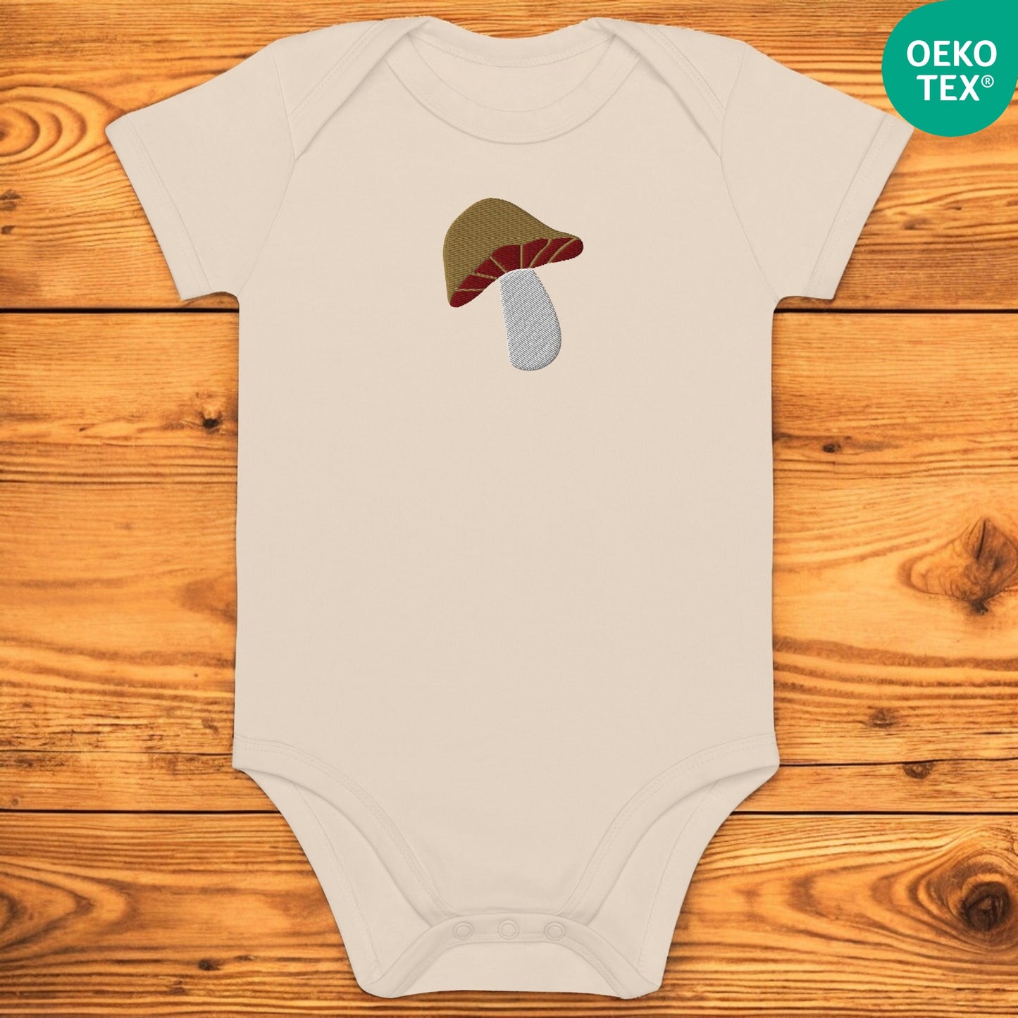 Beige baby body with porcini on a wooden floor
