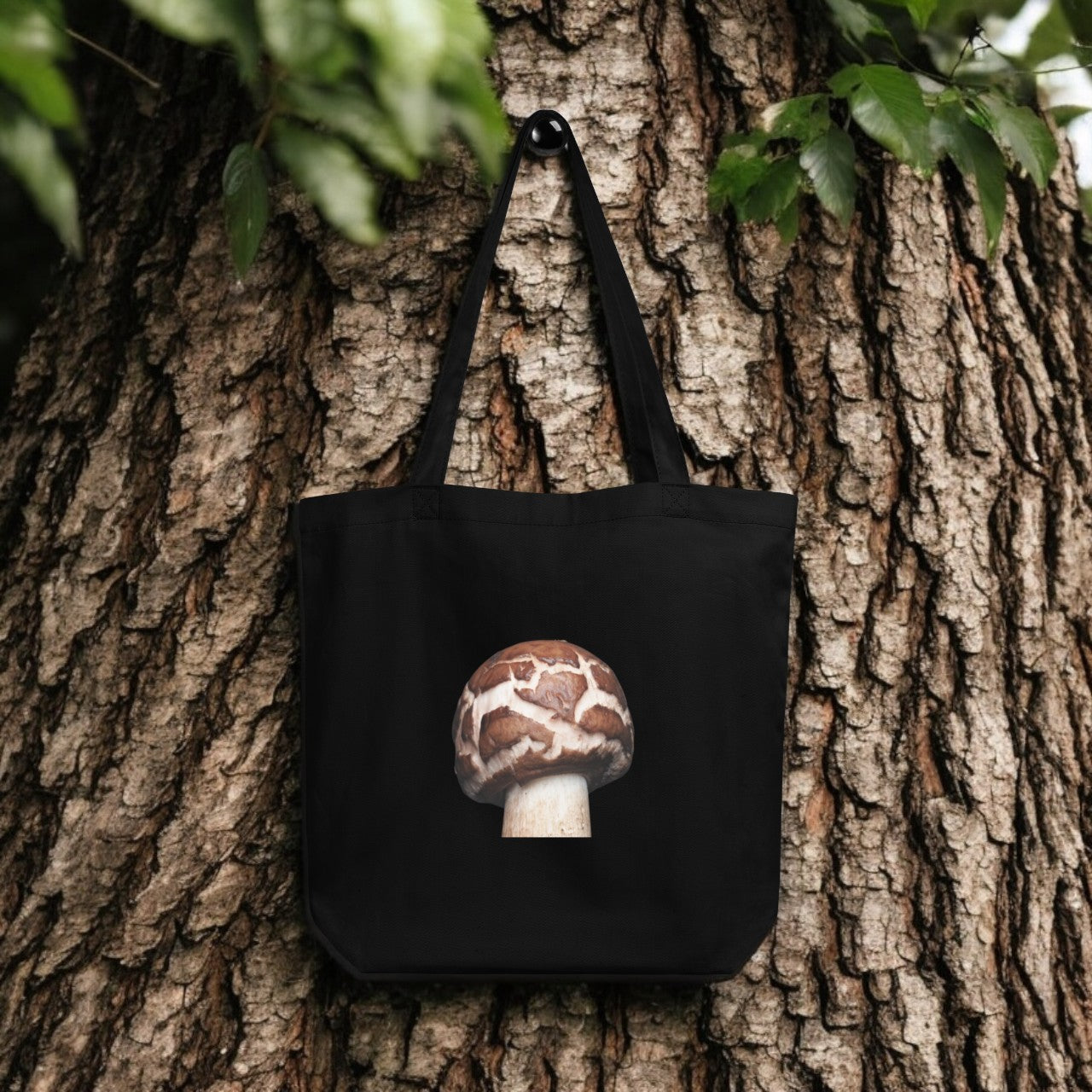 Chlorophyllum Brown and White Patterned Mushroom Tote Bag - black canvas with detailed mushroom underside print, outdoor setting.