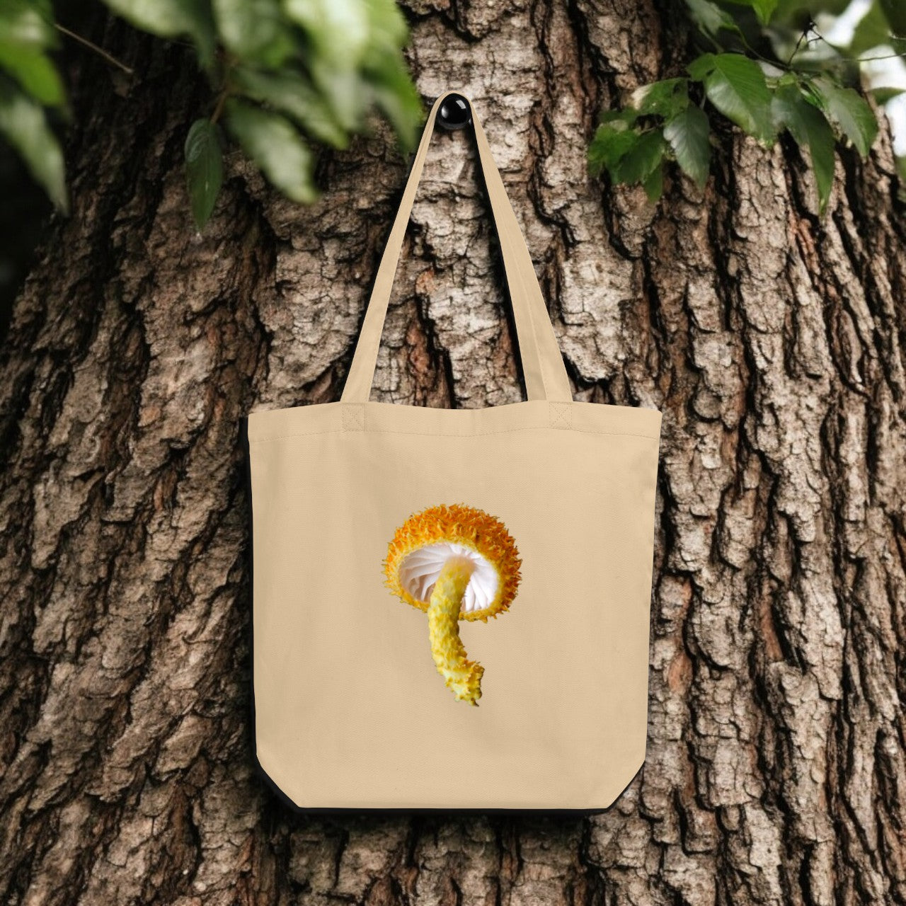 Cryptotrama Golden-Scruffy Collybia Tote Bag - beige canvas with detailed mushroom underside print, outdoor setting.