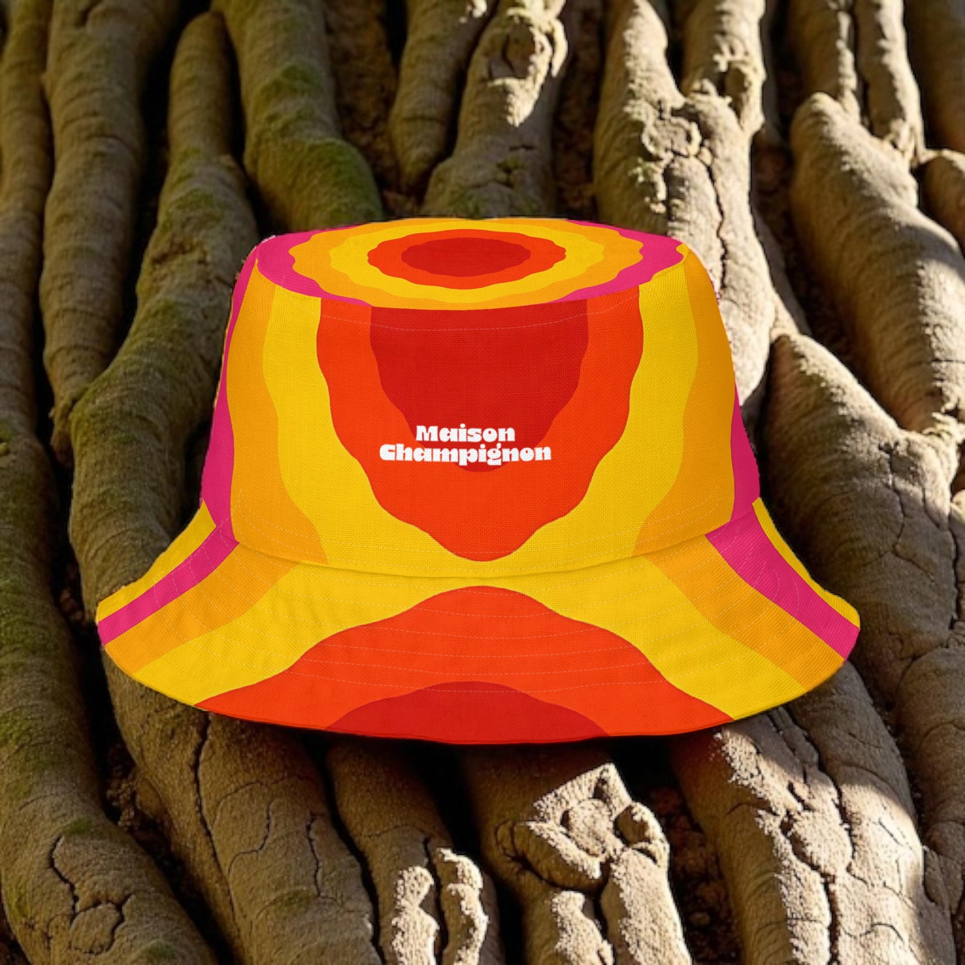 Colorful bucket hat with 'Maison Champignon' logo on a textured surface on a tree