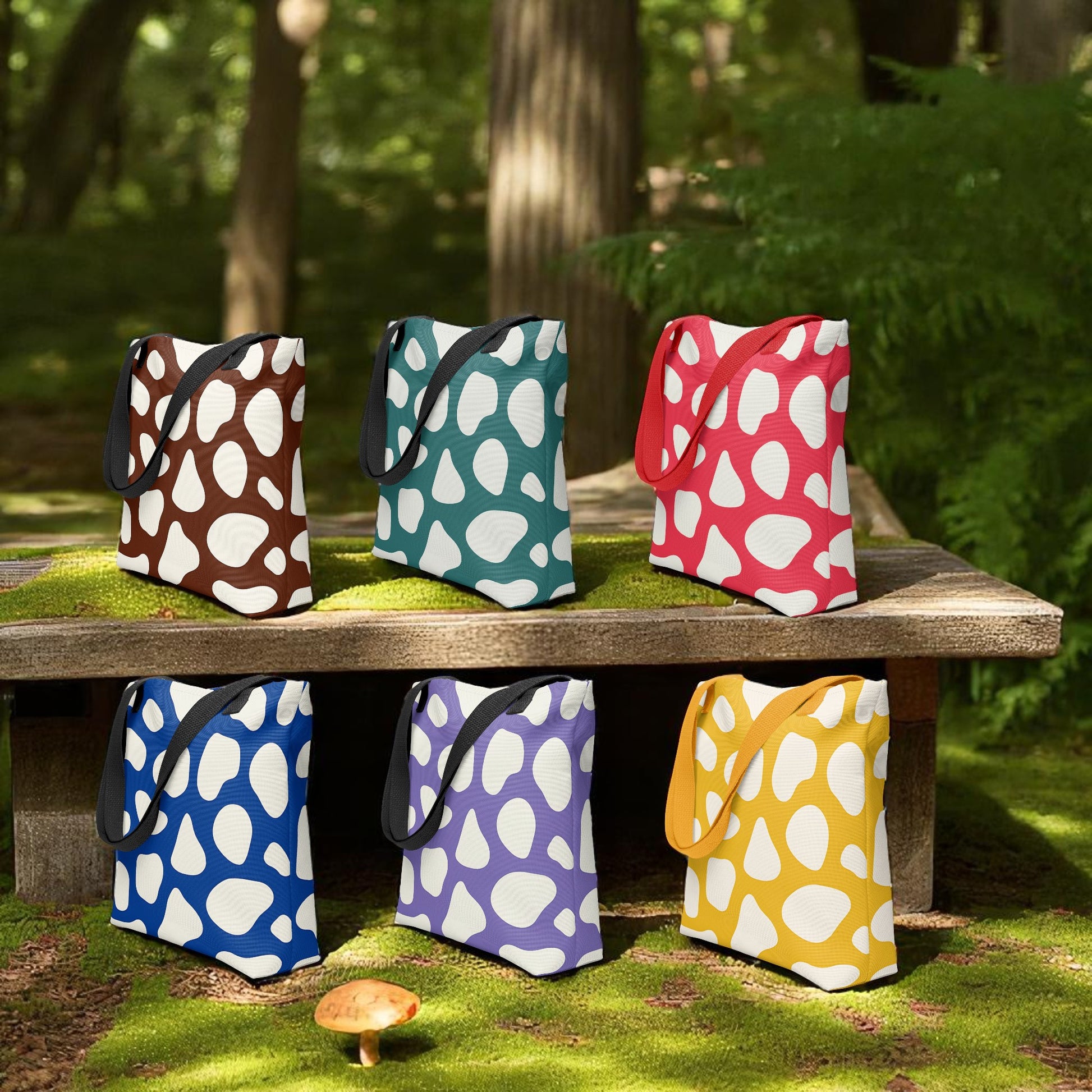 six tote bags with different colors and patterns on display on woods in a natural setting