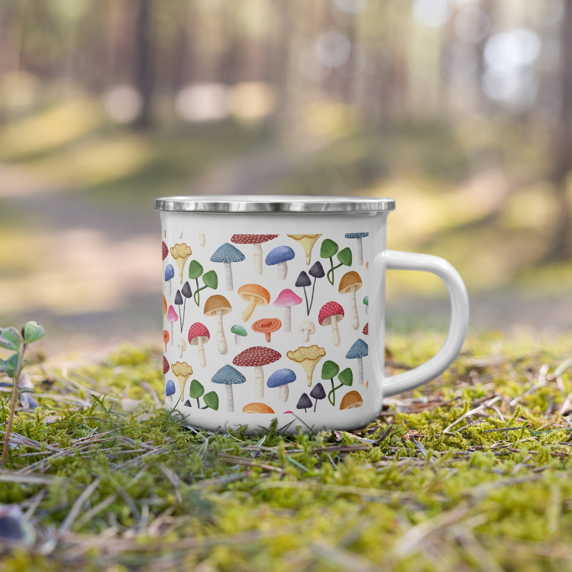 This image features a charming Scavenger Mug, placed amidst a serene forest setting. The mug is white and adorned with a playful and colorful pattern of various mushrooms, making it visually appealing.